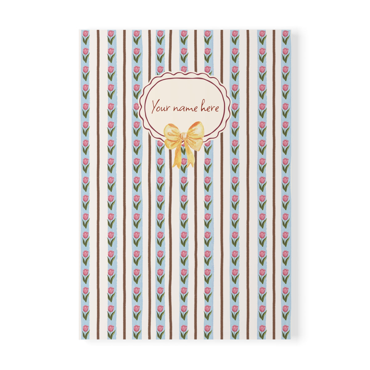 A Softcover A5 Notebook with a vertical striped pattern featuring pink tulips, brown stripes, and a central cream oval label with the text 'Your name here' and a yellow bow illustration, shown on a white background.