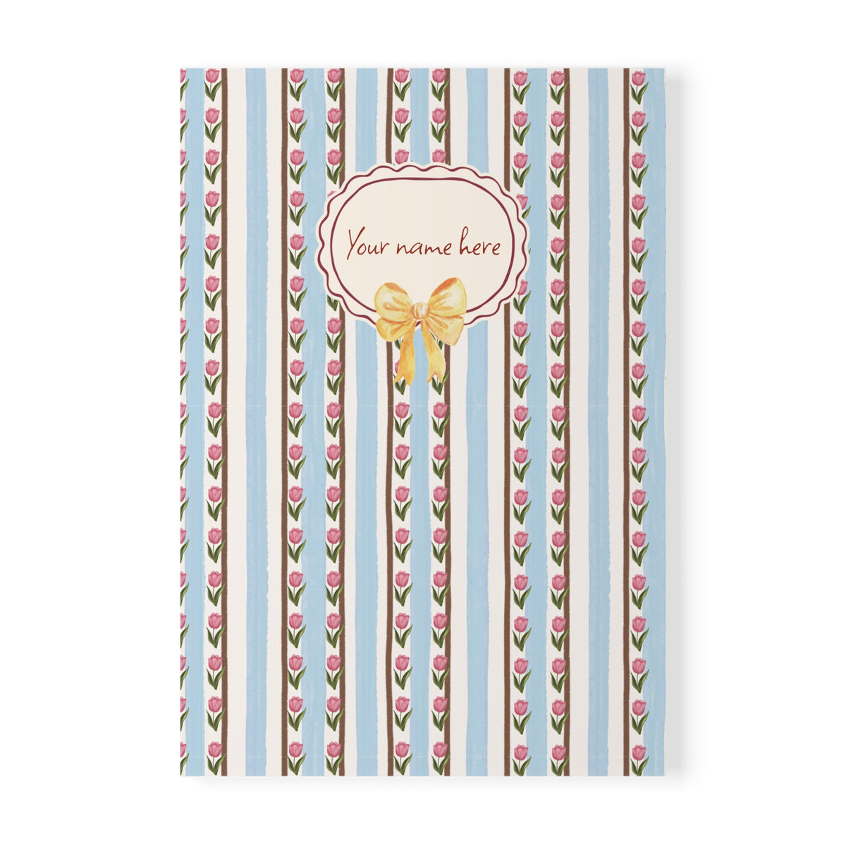 A personalized A5 softcover notebook cover featuring a vertical striped pattern with pink tulips, brown and light blue stripes, and a central cream-colored oval label with a gold bow and the placeholder text 'Your name here'.