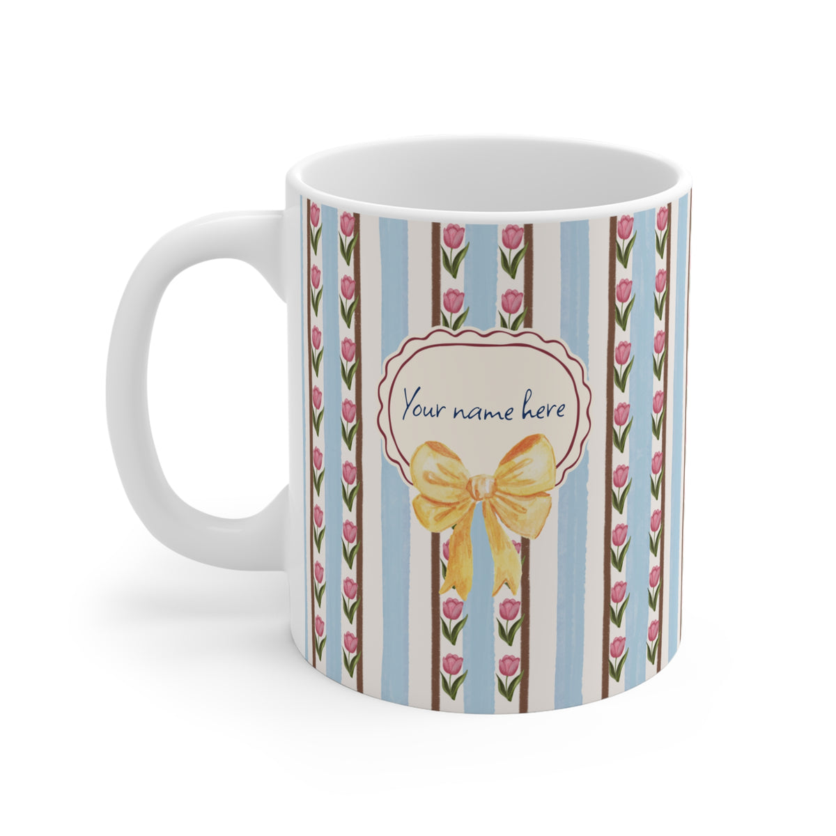 A white ceramic mug with a decorative print featuring vertical light blue and brown stripes, pink tulips, and a central cream label with a yellow bow and the text 'Your name here'.